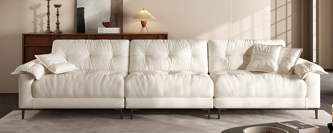 Row of three sectional sofas in white, tan, and dark brown leather in a showroom setting.